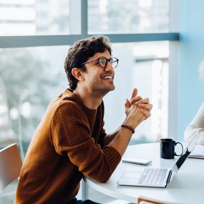 Smiling man and colleague discuss ideas in meeting